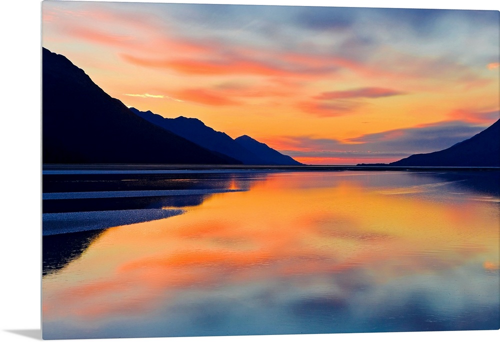 Expansive photograph of the Turnagain Arm in the Cook Inlet in Alaska (AK) during sunset. Calm water is bordered on both s...
