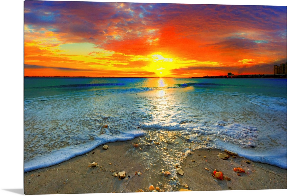 A dark red ocean sunset at seashore. Gentle blue ocean waves roll over the shore.