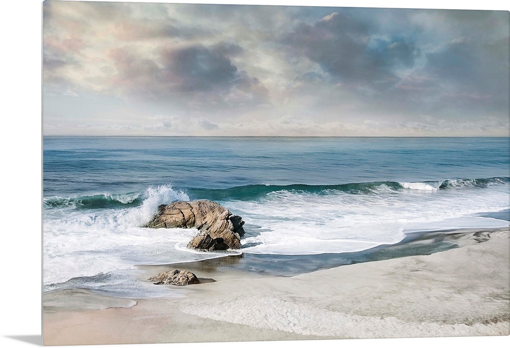 Landscape photograph of waves crashing onto a rock on the sandy shore.