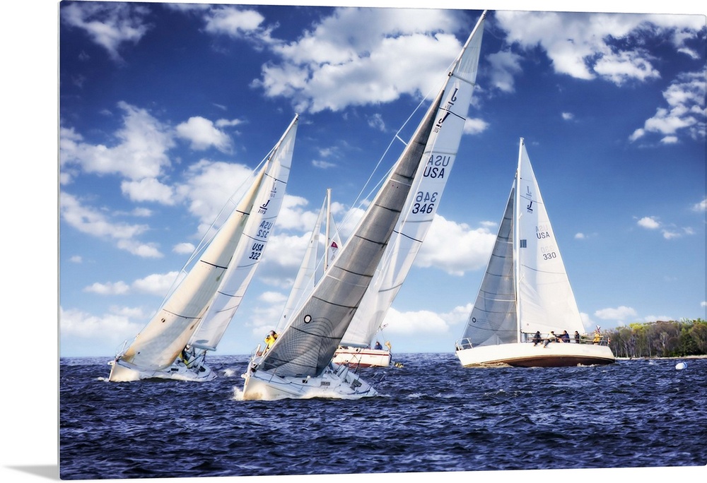 Three white sailboats on the water under a cloudy blue sky.