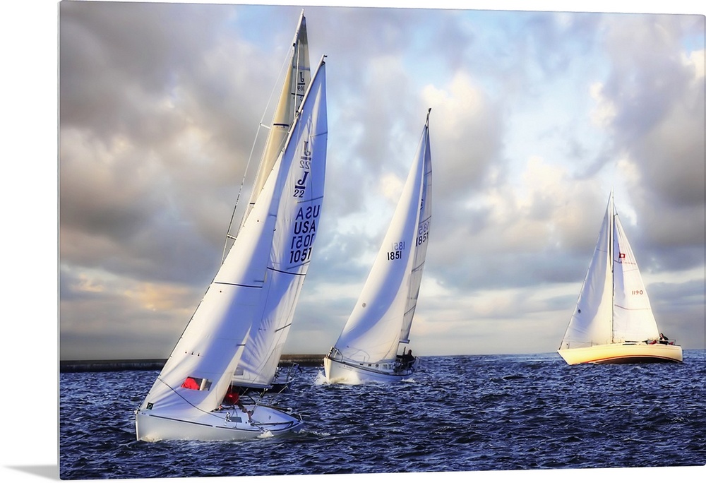 Several sail boats are pictured in open water and the sky filled with grey clouds.