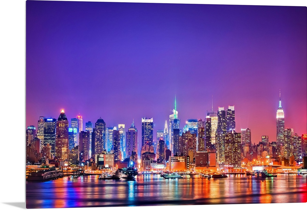 Photograph of New York skyline at night with the Hudson River in foreground.  The building lights are reflected in the water.