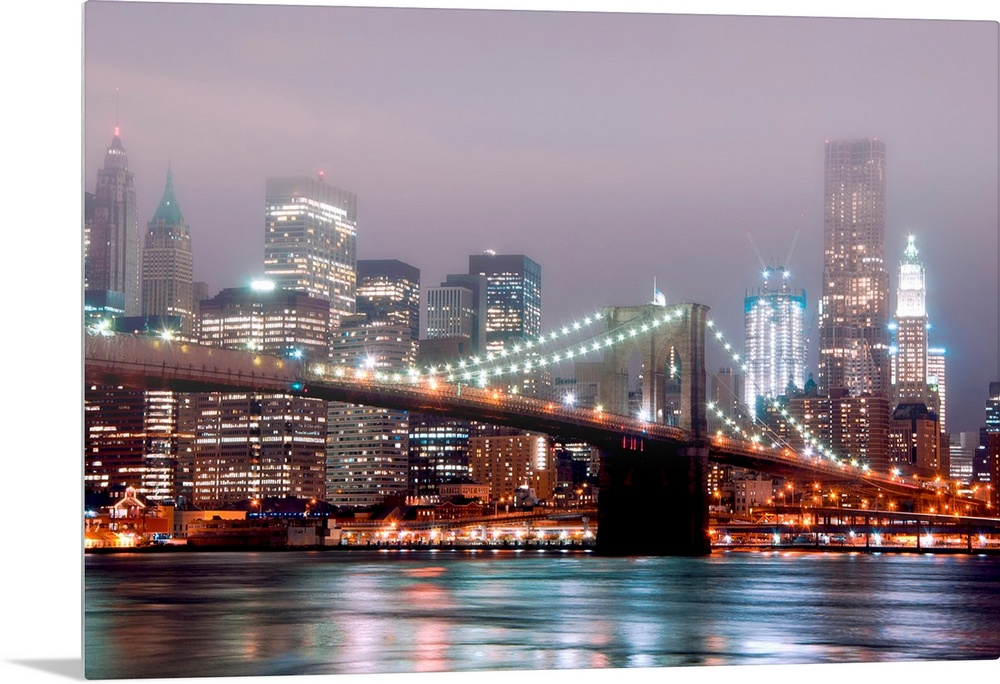 A misty night scene illuminated by urban lights of downtown Manhattan photographed from the Brooklyn shore.