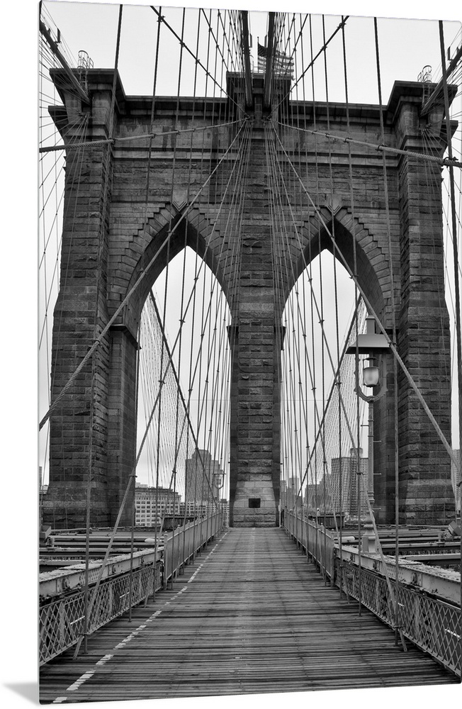 Large, vertical black and white photograph of one of the stone piers surrounded by many cables on the Brooklyn Bridge in N...