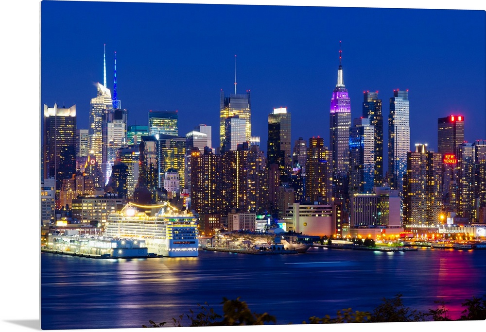 Canvas print of the NYC cityscape lit up in colored lights along a waterfront.