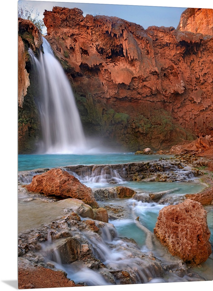 Large photograph showcases water falling down a jagged cliff and splashing into the pool below before moving on down a roc...