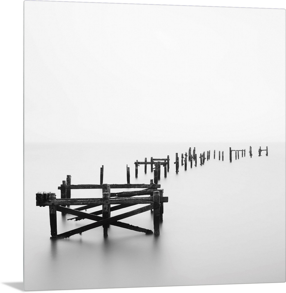 Large photograph focuses on a deteriorating dock sitting alone in a wasteland of fog.