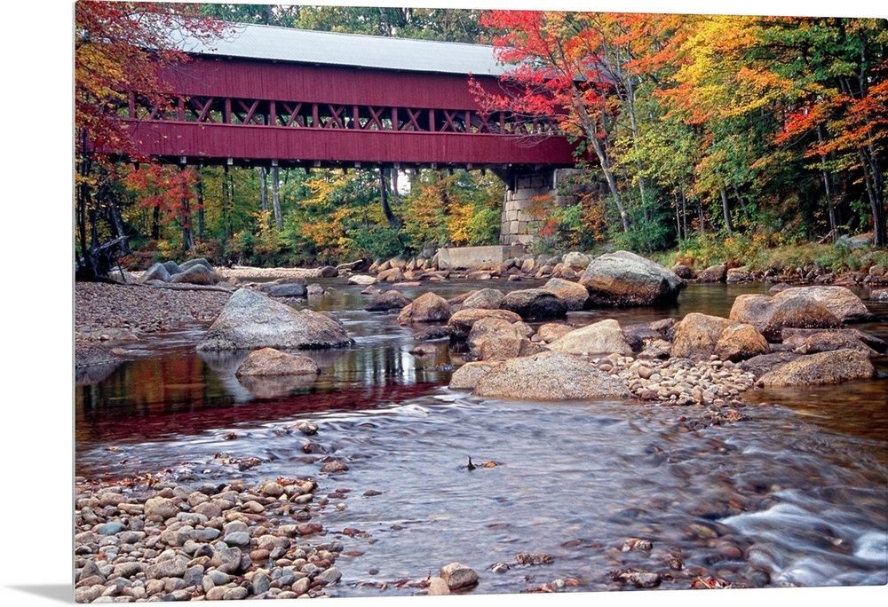 Photograph of the wooden Swift River Bridge located in Conway, New Hampshire that overlooks a river flowing through rocks ...