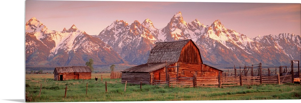 Panoramic photograph of a large barn on a farm in Grand Teton National Park in Wyoming. Located in the background are snow...