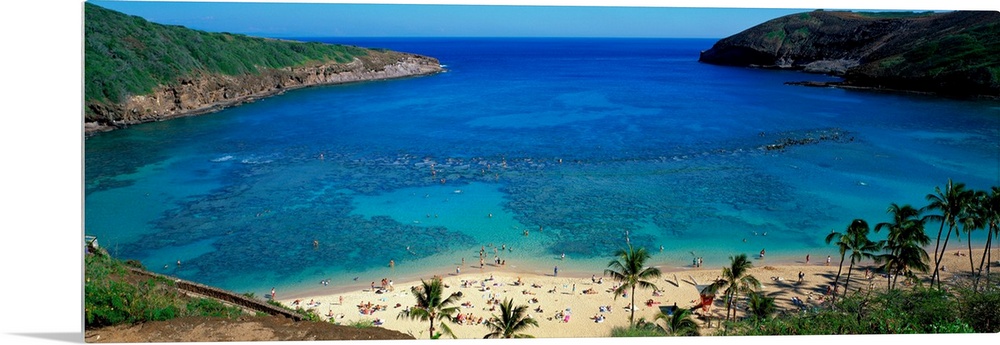 High angle panoramic of a harbor on a tropical island and tourist sunbathing on the shore.