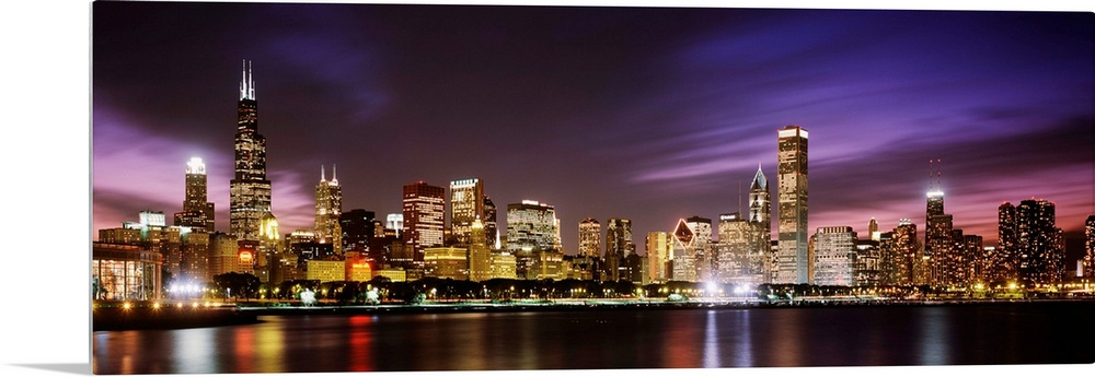 A big cityscape panoramic of downtown Chicagoos lights reflecting off Lake Michigan at night.
