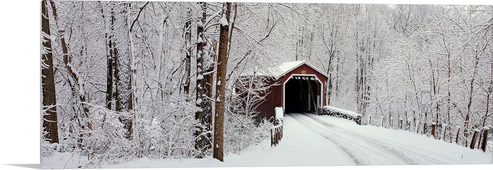 Panoramic photograph of a snow covered bridge in Pennsylvania that is surrounded by a forest.