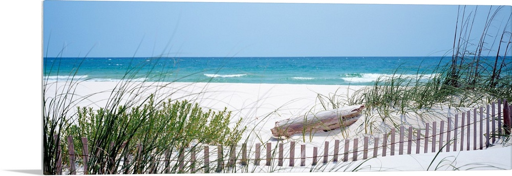Panoramic landscape photograph of a fence buried in the dunes on sandy beach on the Gulf Coast.