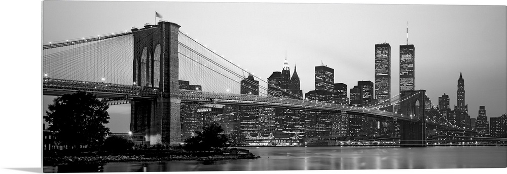 Panoramic photograph of the Brooklyn Bridge against a skyline filled with skyscrapers in New York.  The buildings and brid...