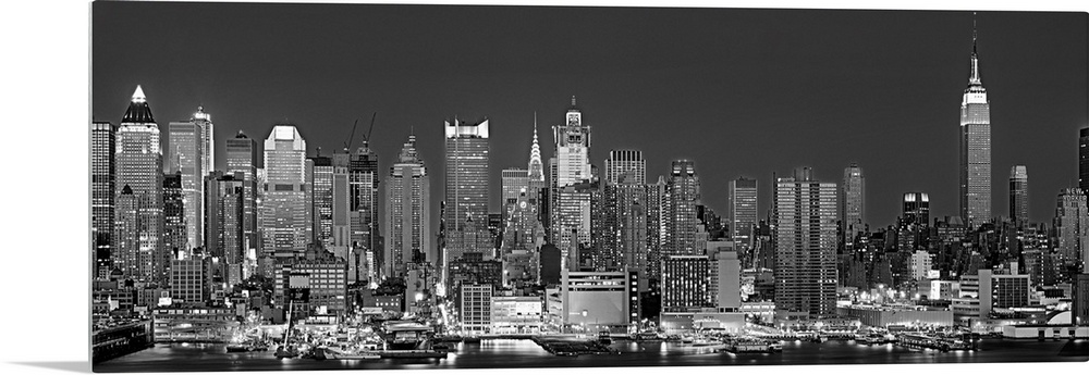 The dense Manhattan skyline, as view from west of the city, is outlined and illuminated by lights in the night.