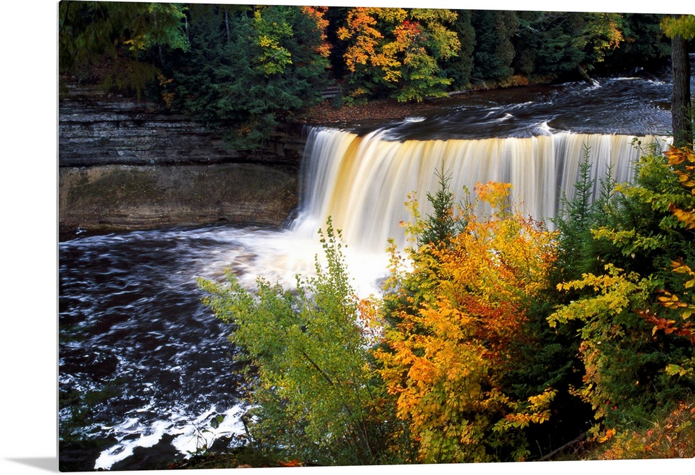 Giant, horizontal photograph of Tahquamenon Falls surrounded by colorful fall foliage in Michigan.