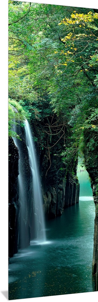 Vertical outdoor shot of a forest, river, and waterfall taken with time-lapsed photography.