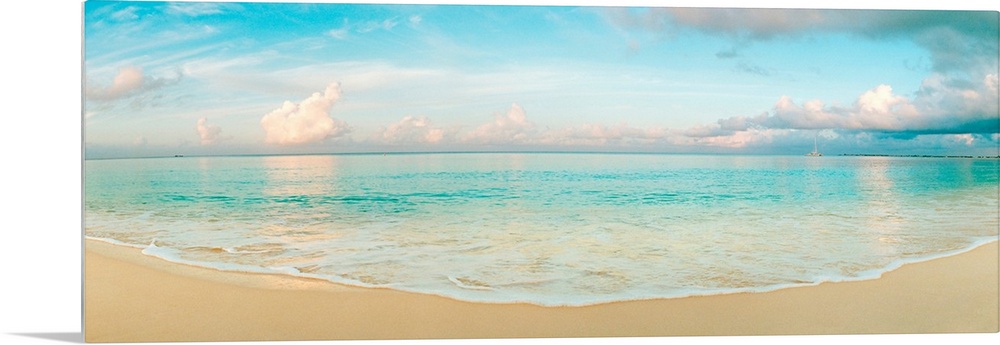 A wide angle panoramic wall hanging of a calm tropical ocean, waves on the beach, and cumulus clouds near the horizon.