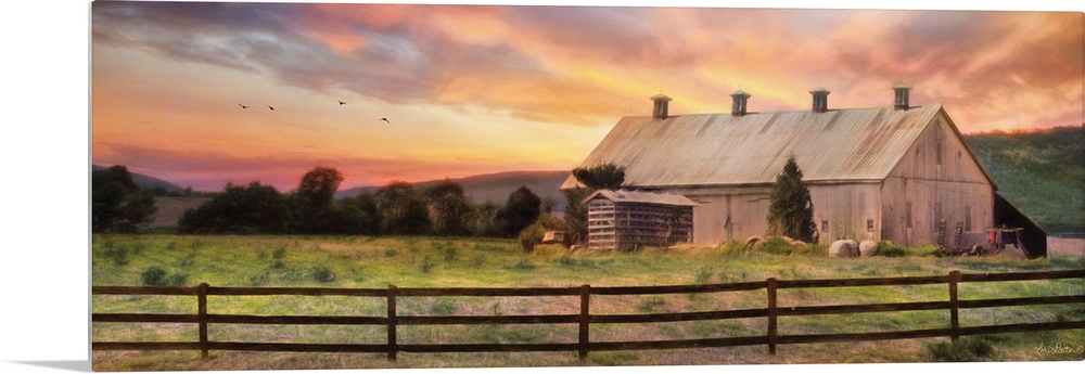 A barn in the countryside with a wooden fence in the early evening.