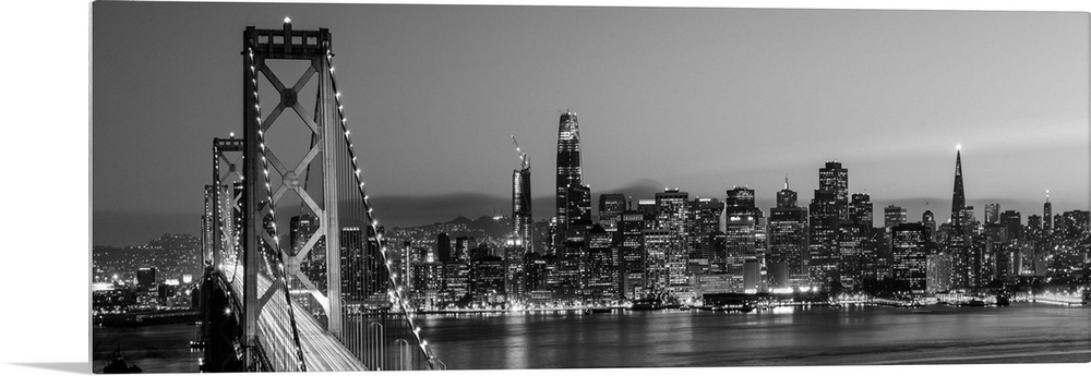 Photograph of the Bay Bridge and the San Francisco skyline lit up at dusk.