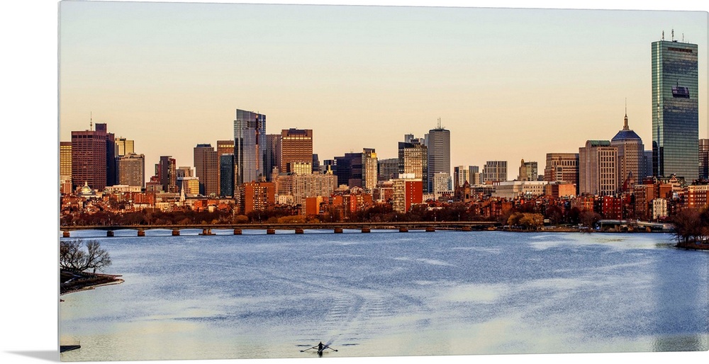 Panoramic view of the Boston City skyline at sunset, seen from across the water.