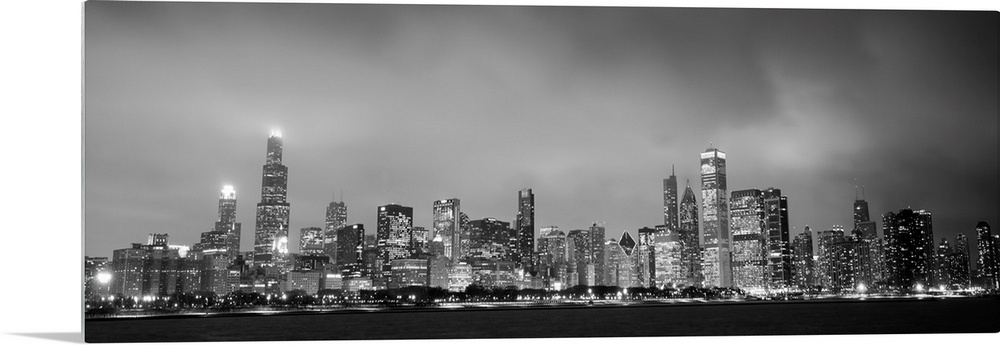 Panoramic view of the Chicago city skyline in the early evening, with city lights reflecting off the clouds above.