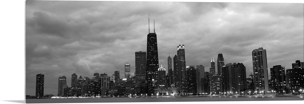 Panoramic view of the Chicago city skyline illuminated in the early evening, seen from across the water.