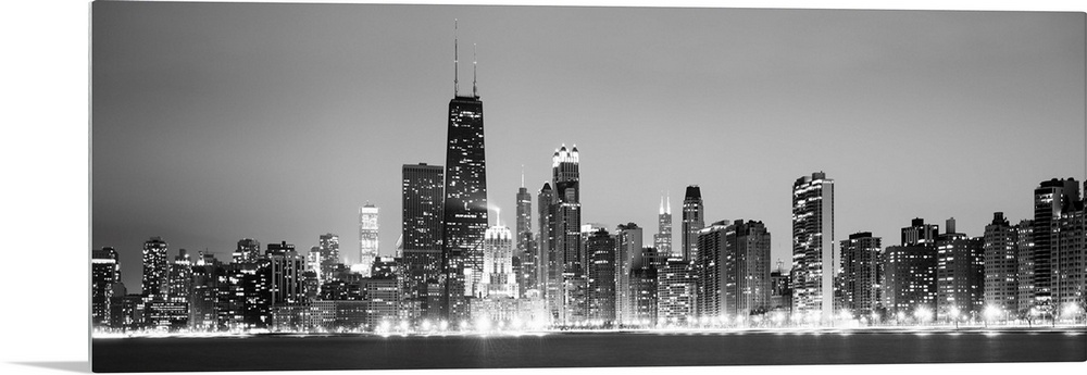Panoramic view of the Chicago city skyline illuminated in the early evening, seen from across the water.