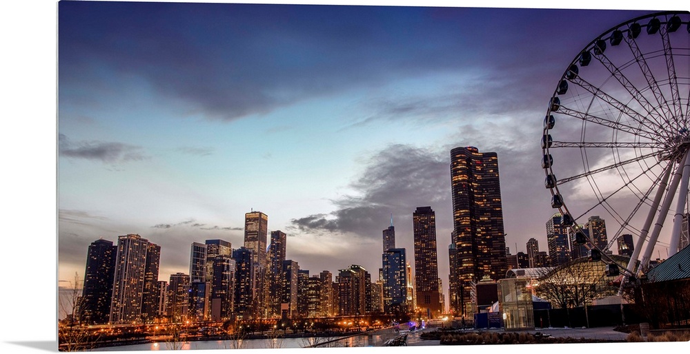 View of the Chicago city skyline illuminated in the early evening with a Ferris Wheel in the foreground.