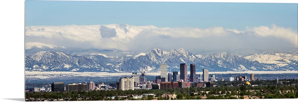 Panoramic photo of a Denver skyline against a backdrop of the Rocky Mountains.