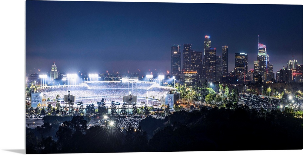Photograph of Dodger Stadium lit up on a game night with the Los Angeles skyline on the right.