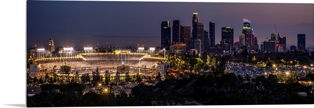 Panoramic photograph of Dodger Stadium lit up on a game night with the Los Angeles skyline on the right.