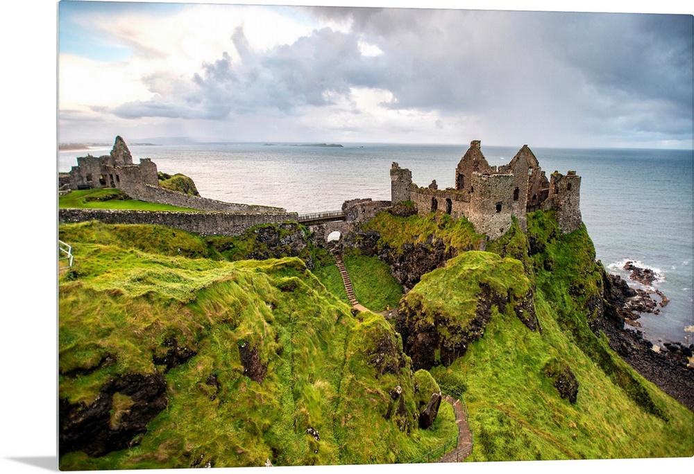 Landscape photograph of Dunluce Castle next to the ocean, taken from a higher point.