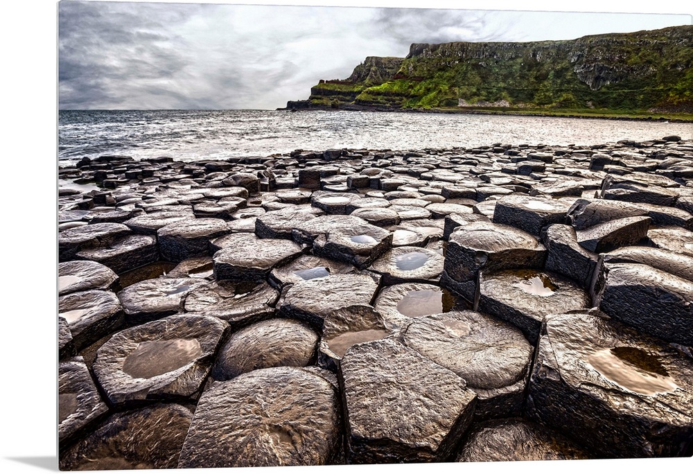 Landscape photograph of the basalt columns on Giant's Causeway with rocky cliffs and the Atlantic Ocean in the background.