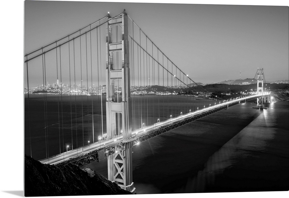 Cool toned photograph of the Golden Gate Bridge lit up at twilight with the city lights in the background.