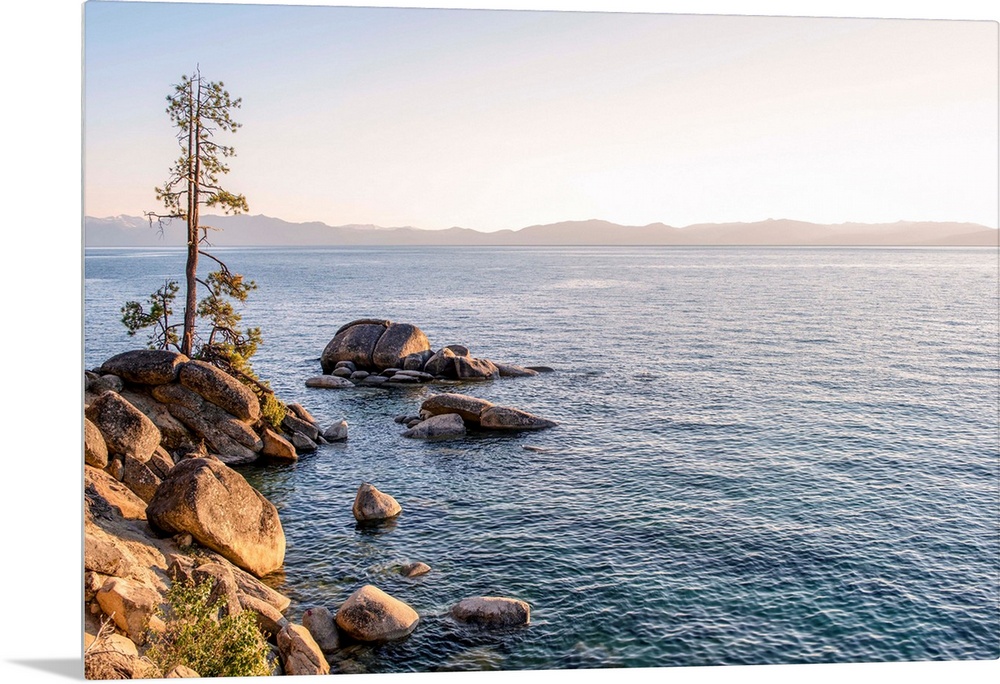 View of Lake Tahoe's rocky shore with mountain landscape in the background in California and Nevada.