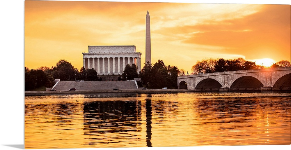 The Lincoln Memorial and Washington Monument seen from the Potomac River with orange clouds at dusk.