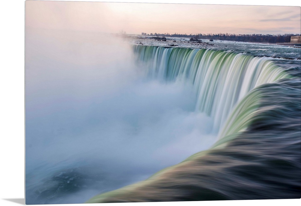 Water cascades down at Horseshoe Falls while dramatic mist ascents to meet the rising sun.