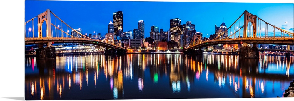 Panoramic photo of downtown Pittsburgh at night with the Rachel Carson Bridge and the Andy Warhol Bridge over the Alleghen...