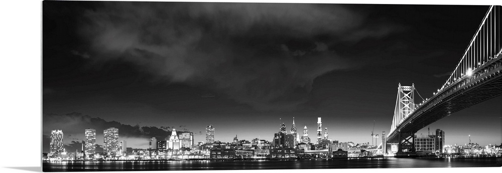 Panoramic photo of the Philadelphia city skyline at night, with the Benjamin Franklin Bridge on the right.