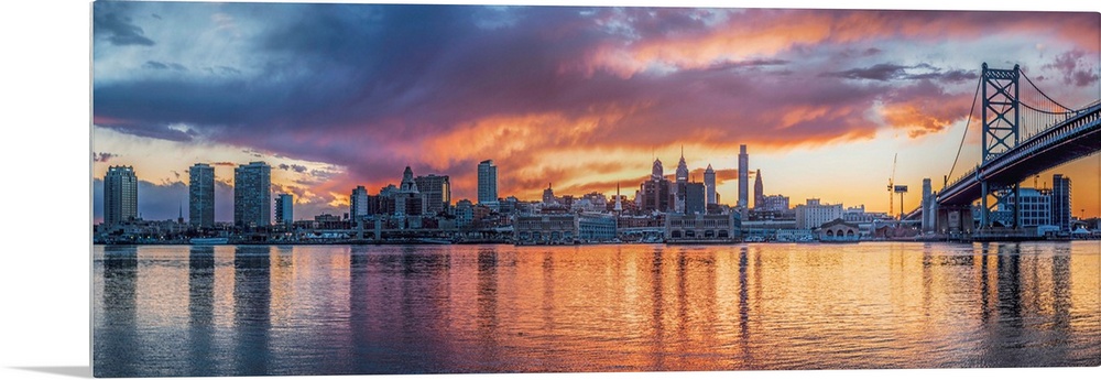 Panoramic view of a fiery sunset over the Philadelphia city skyline, with the Benjamin Franklin Bridge on the right.