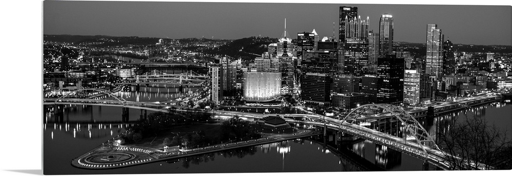 Panoramic photo of the city of Pittsburgh illuminated at night, with Point State Park in the foreground.