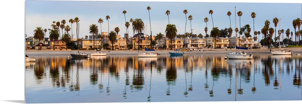 Panoramic photograph of beach houses, palm trees, and boats on the San Diego coast reflecting into the water.