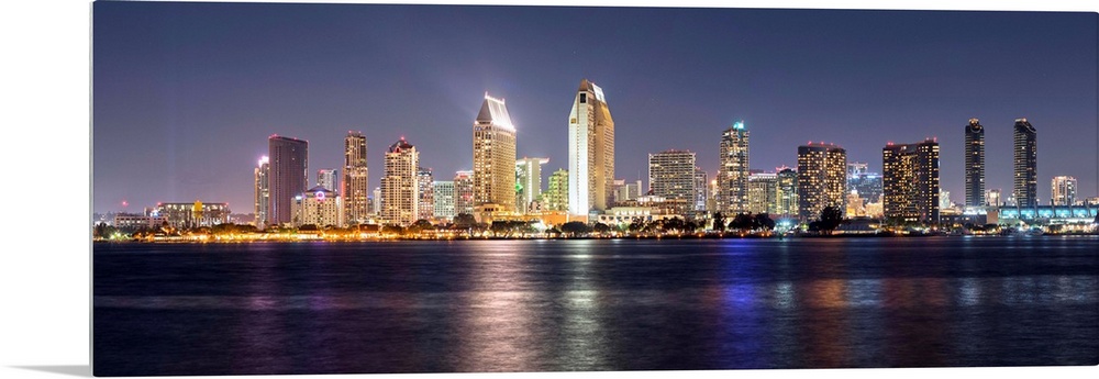 Panoramic photograph of the San Diego, California skyline lit up at night from across the water.