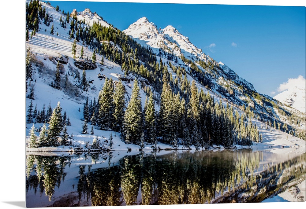 Summer snow on pine trees and the mountain side at the edge of Maroon Lake in the Maroon Bells, Aspen, Colorado.