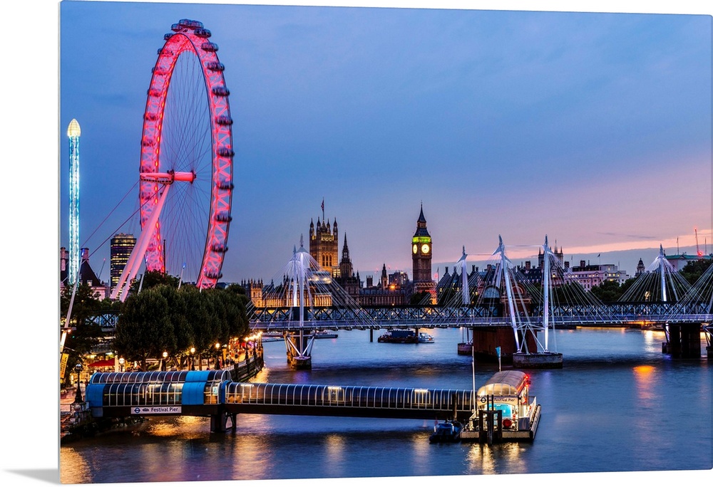 Photograph of the London Eye lit up at night with Big Ben in the background and the Golden Jubilee Bridge going over River...