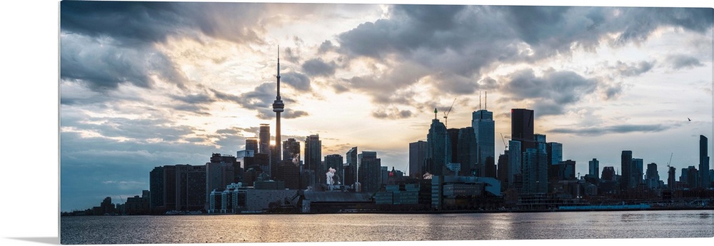 Toronto city skyline under a dramatic sunset with clouds overhead, Ontario, Canada.