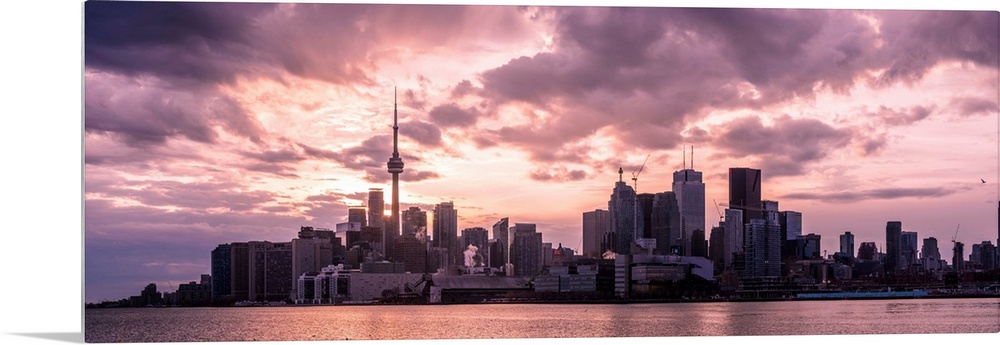 Toronto city skyline under a dramatic sunset with clouds overhead, Ontario, Canada.