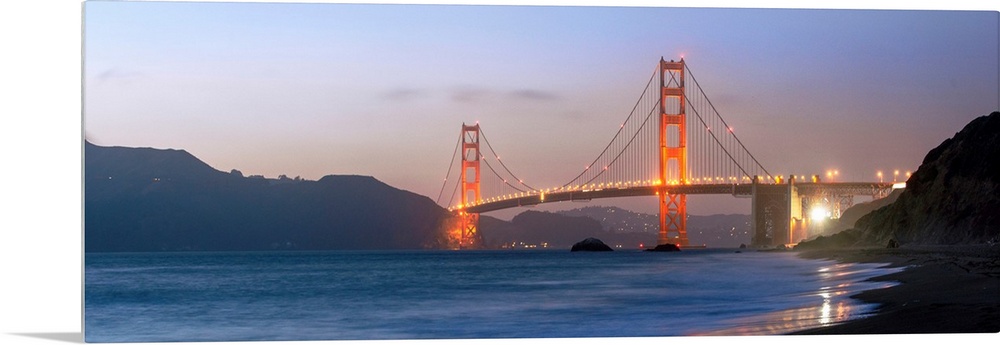 Panoramic photograph at twilight of the Golden Gate Bridge taken from the shore.