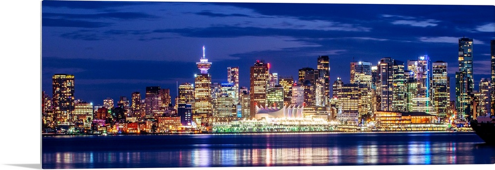 Panoramic photograph of the Vancouver, British Columbia skyline lit up on a dark purple night and reflecting bands of colo...